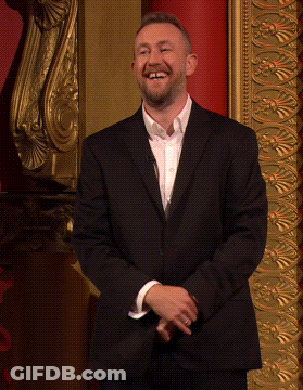 Smiling Man In Suit Before Gold Wall GIF