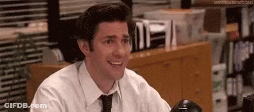 Smiling Man In White Shirt And Black Tie At Desk GIF