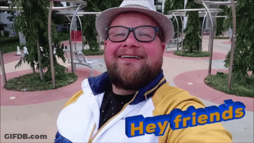 Smiling Man With Glasses And Hat Saying Hey Friends GIF