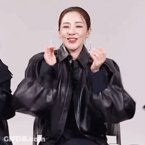 Smiling Woman Black Leather Jacket Hoop Earrings Making Heart GIF