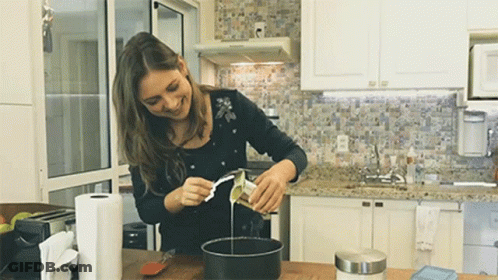 Smiling Woman Pouring Liquid Into Pan GIF