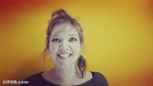 Smiling Woman With Bun In Front Of Yellow Wall GIF