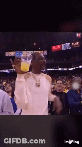 Snoop Dogg Is Holding A Cup Of Orange Juice In Front Of A Crowd GIF