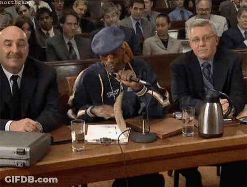 Snoop Dogg Is Sitting At A Table With A Microphone In Front Of A Crowd Of People GIF