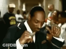 Snoop Dogg Is Wearing A Suit And Tie And Eating A Piece Of Food . GIF
