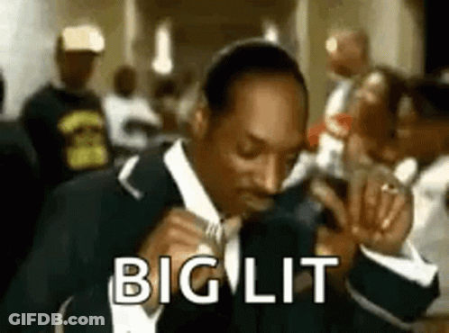 Snoop Dogg Is Wearing A Suit And Tie And Singing Into A Microphone In A Crowded Room . GIF