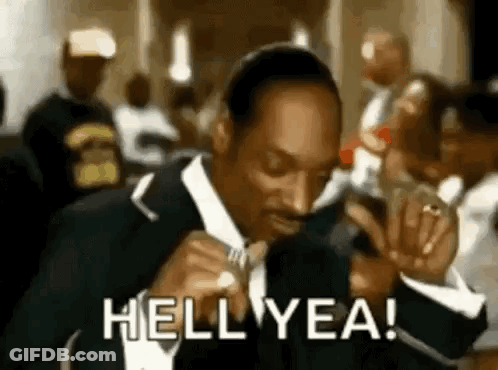 Snoop Dogg Is Wearing A Suit And Tie And Smoking A Cigarette In A Crowd . GIF