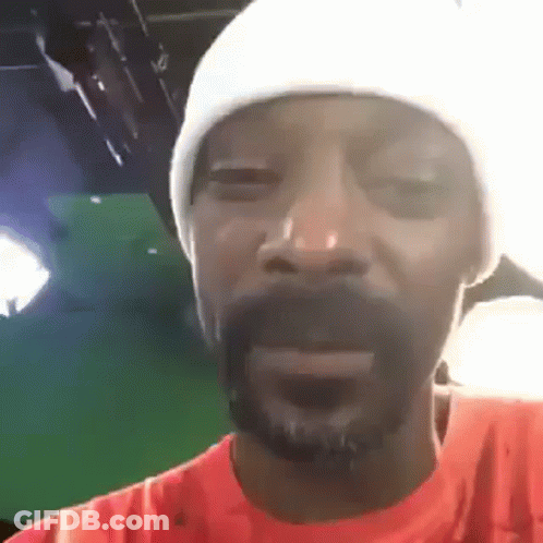 Snoop Dogg Is Wearing A White Hat And An Orange Shirt While Making A Funny Face . GIF
