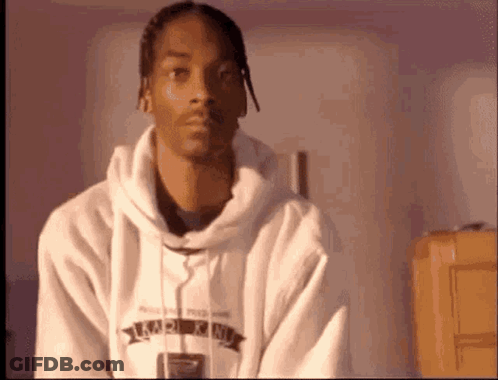 Snoop Dogg Is Wearing A White Hoodie And Looking At The Camera While Sitting In A Room . GIF