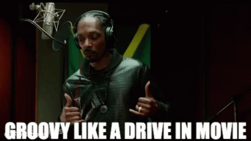 Snoop Dogg Is Wearing Headphones In Front Of A Microphone And Giving A Thumbs Up . GIF