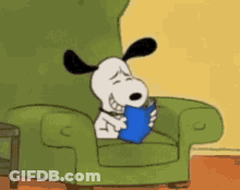 Snoopy Is Reading A Book While Sitting In A Green Chair . GIF
