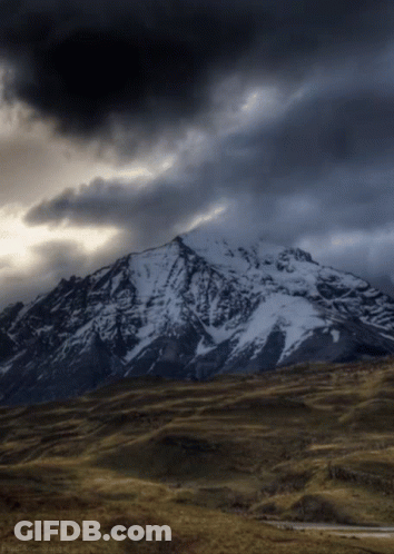 Snow-Covered Mountain Under Dark Cloudy Sky GIF