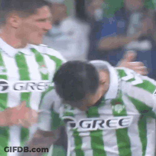 Soccer Player In Green And White Striped Jersey Being Hugged GIF