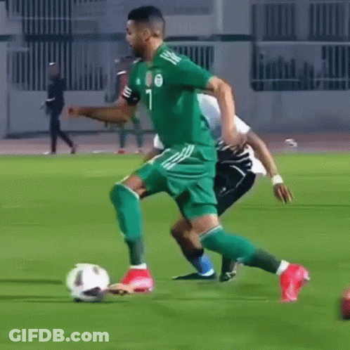 Soccer Player In Green Jersey Kicking Ball Tackled GIF