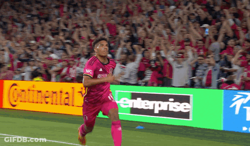 Soccer Player In Pink Jersey Running Past Enterprise Sign GIF