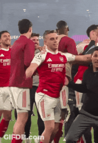 Soccer Player In Red Emirates Jersey Surrounded By Teammates GIF