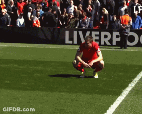 Soccer Player Kneeling In Front Of Liverpool Sign GIF