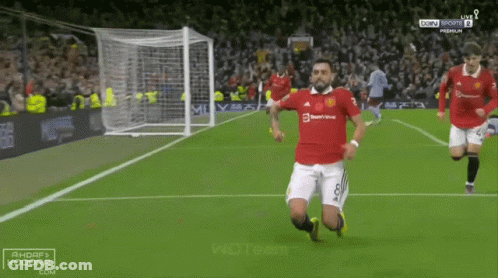 Soccer Player Kneeling While Another Runs Toward Him GIF