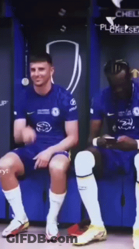 Soccer Player Sitting On Bench While Teammate Looks At Phone GIF