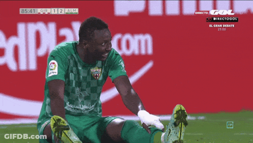 Soccer Player Stretching Legs In Front Of Coca Cola Sign GIF