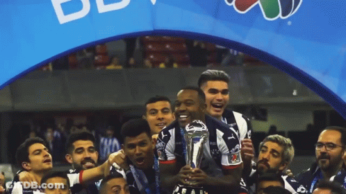 Soccer Players Celebrate With Trophy In Front Of BB Banner GIF