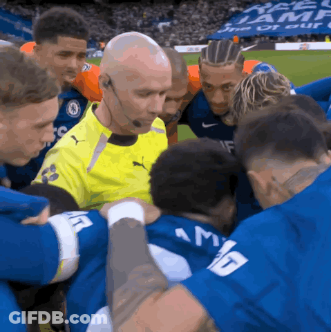 Soccer Players Huddle Around Referee In Yellow Puma Jersey GIF