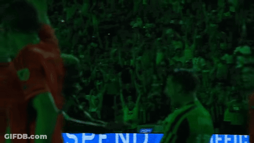 Soccer Players Hugging In Front Of Green Crowd GIF