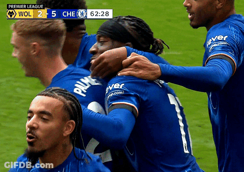 Soccer Players Hugging On Field With Premier League Scoreboard GIF