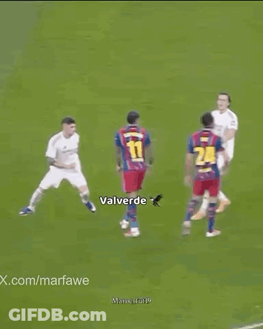 Soccer Players Standing Around Player Lying On Field GIF