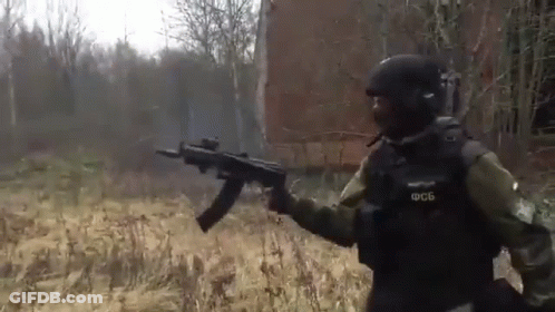Soldier Holding Gun In Field In Front Of Building GIF