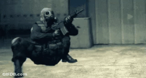Soldier Wearing Gas Mask Holding Gun Sitting On Floor GIF