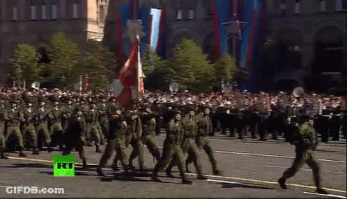 Soldiers Marching Down Street With Green RT Logo GIF