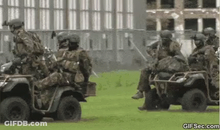 Soldiers Riding ATVs On Grassy Field GIF