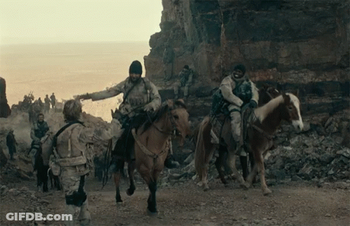 Soldiers Riding Horses On Dirt Road Near Ocean GIF