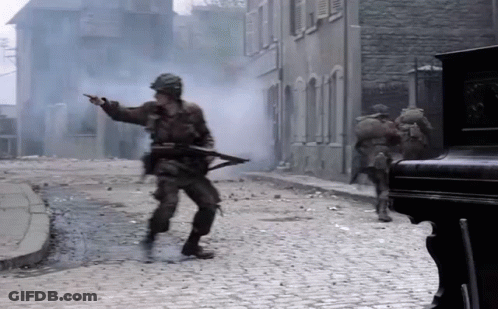 Soldiers Walking And Pointing On Cobblestone Street GIF