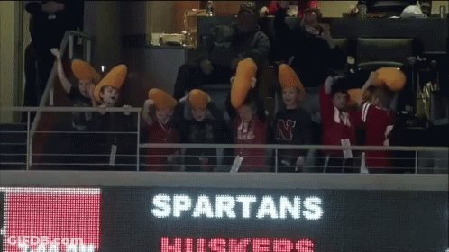 Spartans Cheerleaders Sitting In Front Of Scoreboard GIF
