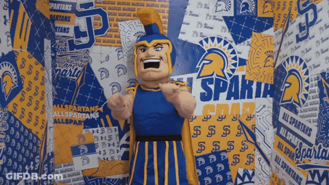 Spartans Mascot In Front Of Spartans Logos Wall GIF