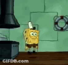Spongebob Squarepants Is Standing On A Wooden Table In Front Of A Stove . GIF