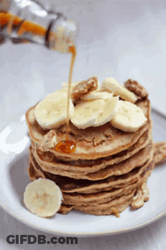 Stack Of Pancakes With Bananas And Walnuts Being Poured Syrup GIF