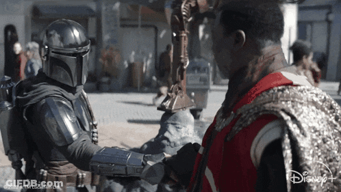 Star Wars Man In Red Vest Shaking Hands With Helmeted Man GIF