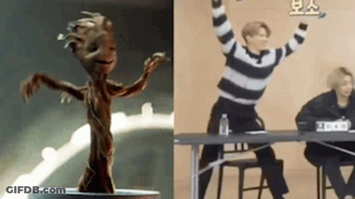 Statue Of Groot Standing Next To Picture Of Man At Table GIF
