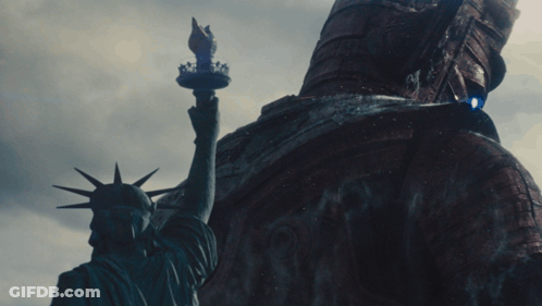 Statue Of Liberty Standing Next To Giant Statue GIF