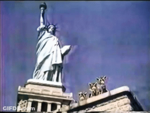 Statue Of Liberty Surrounded By Giraffes And Building GIF