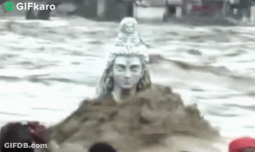 Statue Of Man Sitting On Sand Pile In Ocean GIF