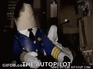 Stuffed Animal In Pilot Uniform Sitting In Dark Room With Cardboard Head GIF