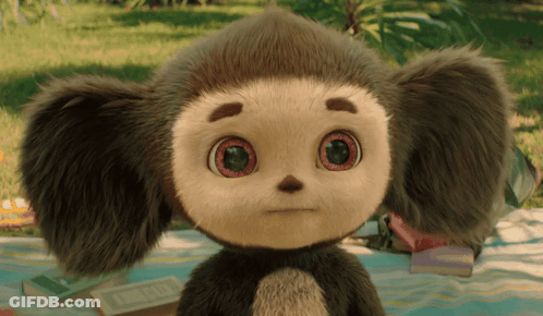 Stuffed Animal With Big Eyes Sitting On Blanket In Grass GIF