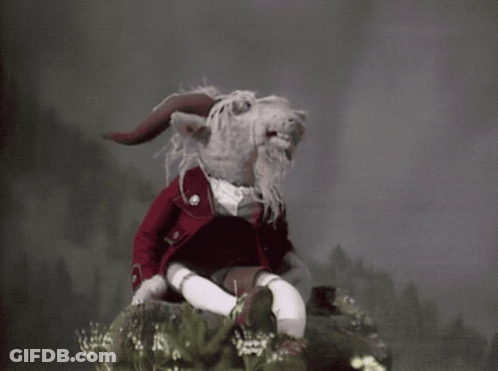 Stuffed Animal With Horns And Beard Sitting On Rock GIF