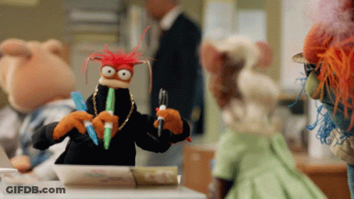 Stuffed Animals Around Table One With Pen In Mouth GIF
