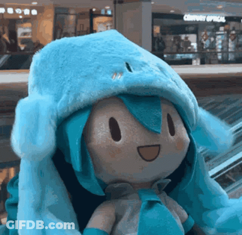 Stuffed Doll In Blue Hat Sitting On Escalator GIF