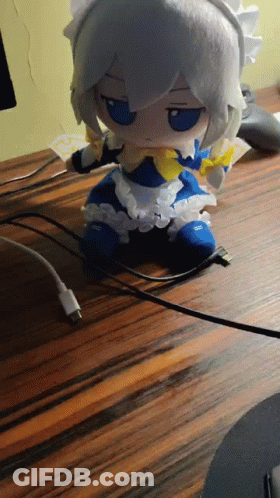 Stuffed Doll In Maid Outfit Sitting On Wooden Table GIF